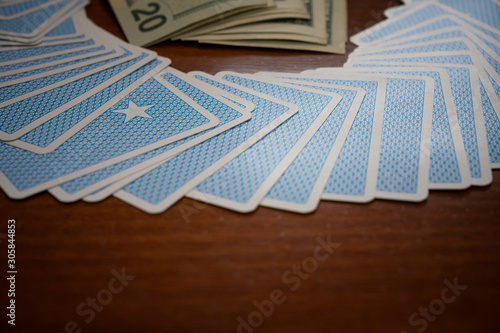 Blue cards gambler game with money on wooden table background.