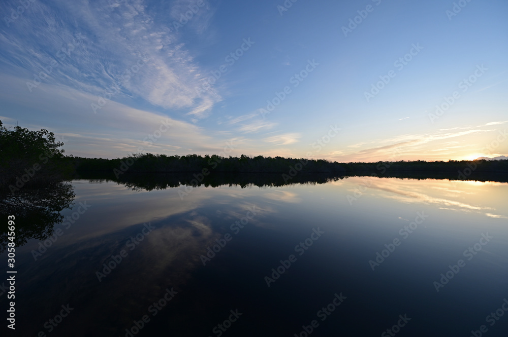Sunrise cloudscape reflected on calm water of West Lake in Everglades National Park, Florida.