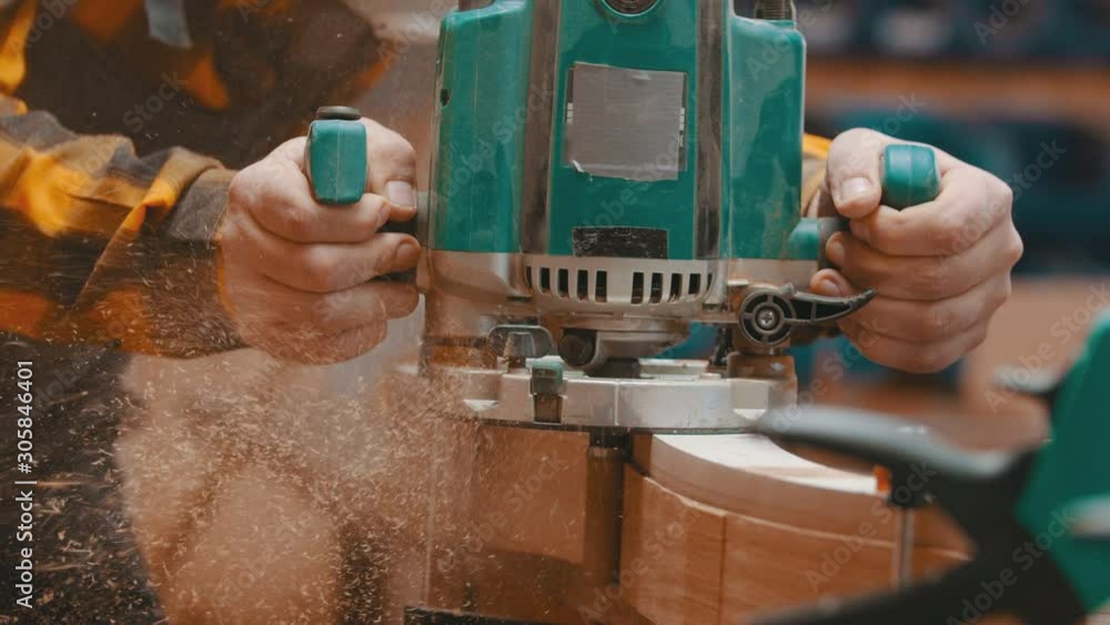 Carpentry indoors - a woodworker polishes a top of wooden plank