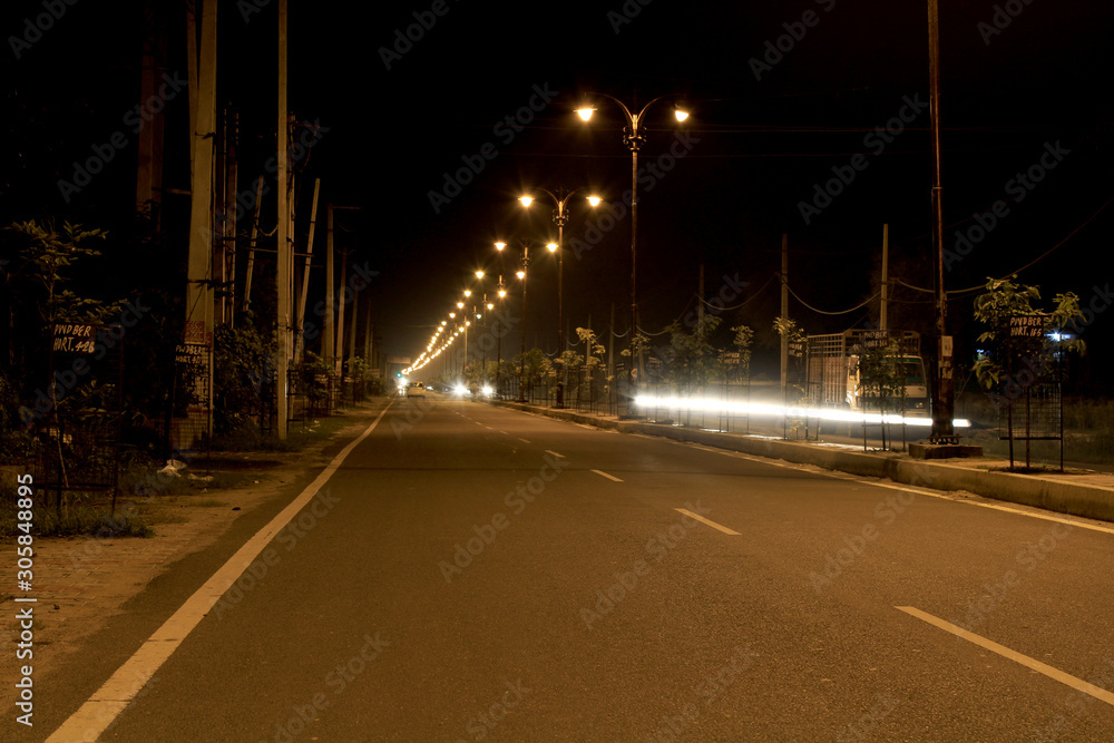 Rohtak, Haryana, India - July 29, 2018: Empty road at night illuminated with street light.