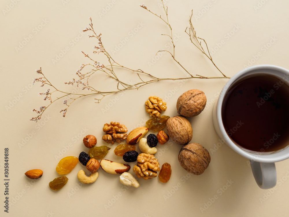 A Cup of tea, nuts and raisins next to dried flowers on a yellow background A Cup of tea, nuts and raisins next to dried flowers on a yellow background