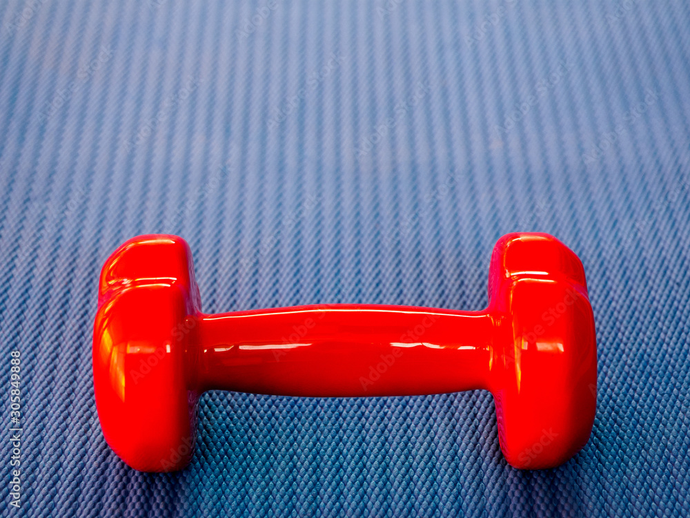 Fototapeta premium Red dumbbell on blue Mat for fitness or yoga