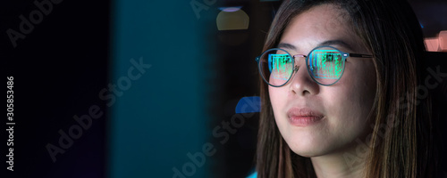 Obraz na płótnie Banner, web page or cover template of Asian Businesswoman working hard and looking the digital graphic on the table with front of computer desktop in workplace at late,Work hard and too late concept w salonie