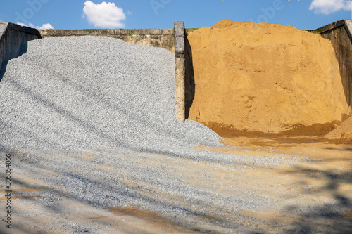 Heap of stone and sand at a construction material warehouse for sale. Stone and Sand are used as aggregates in concrete mix for construction.