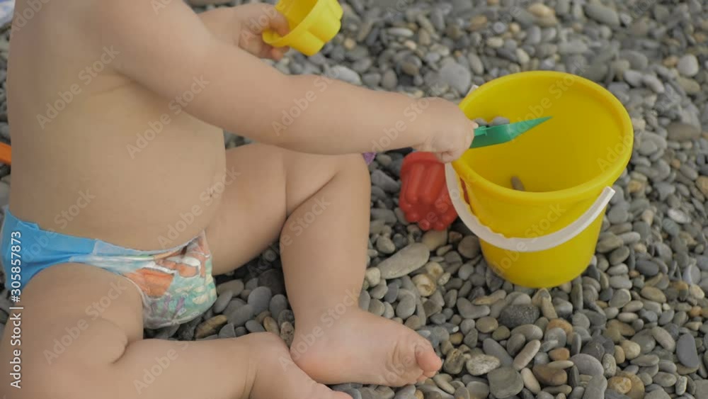 Closeup of little girl legs on pebble beach with toys Closeup of little girl legs on pebble beach with toys