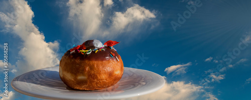 Festive sweet donut on saucer isolated on background with clouds