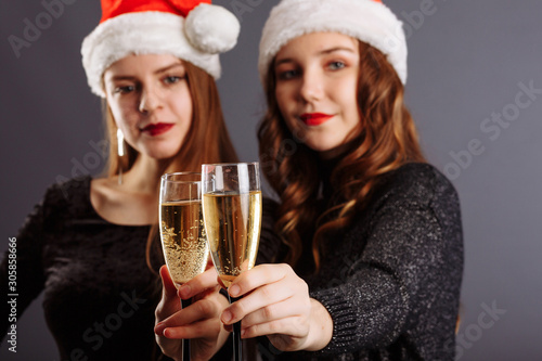 Two Beautiful Girls With Glasses Of Champagne Celebrating NEW Year party. Portrait Of Smiling Young Women With Long Hair, Stylish Hairstyle, Sexy Glamour Makeup Beauty Face With Drink. High-Quality