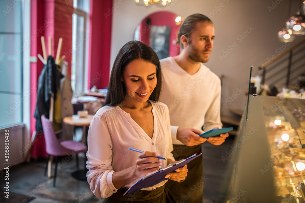 Businesswoman making notes while ordering foods with husband Businesswoman making notes while ordering foods with husband