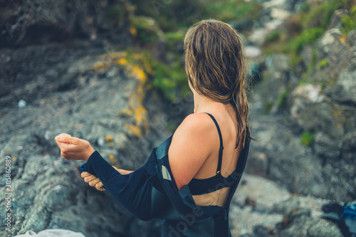 Fotografie Woman on beach removing her wetsuit