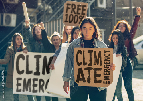 Young woman with poster in front of people protesting about climate changing on the street. Meeting about problem in ecology, environment, global warming, industrial influence, climate emergency. photo