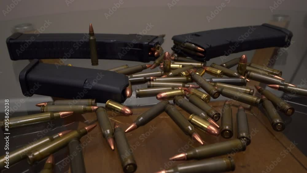 Slider shot showing hoard of AR-15 ammo and gun magazines laying on a glass table Slider shot showing hoard of AR-15 ammo and gun magazines laying on a glass table