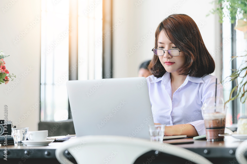 Portrait of young businesswoman wearing eyeglasses working with laptop in modern office. Portrait of young businesswoman wearing eyeglasses working with laptop in modern office.