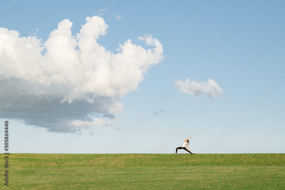 Young woman silhouetted on grassy hill doing yoga Young woman silhouetted on grassy hill doing yoga