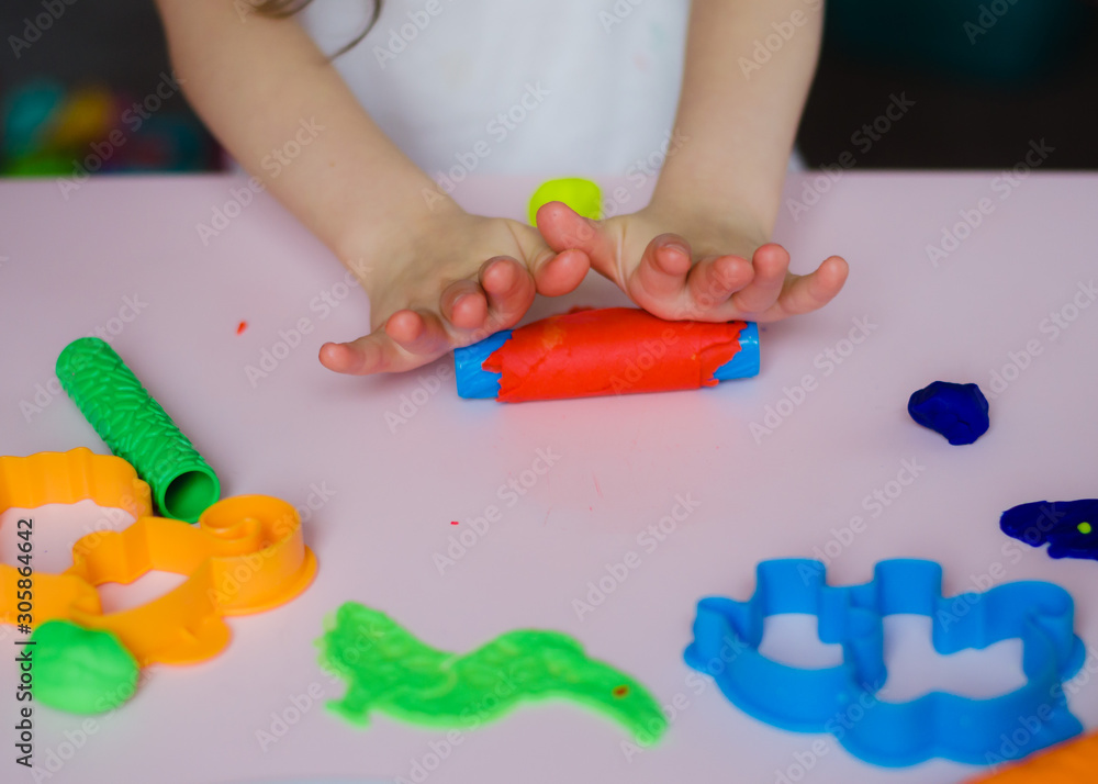 Child hands playing with colorful clay. Homemade plastiline. Plasticine.  play dough. Girl molding modeling clay. Homemade clay. Stock Photo