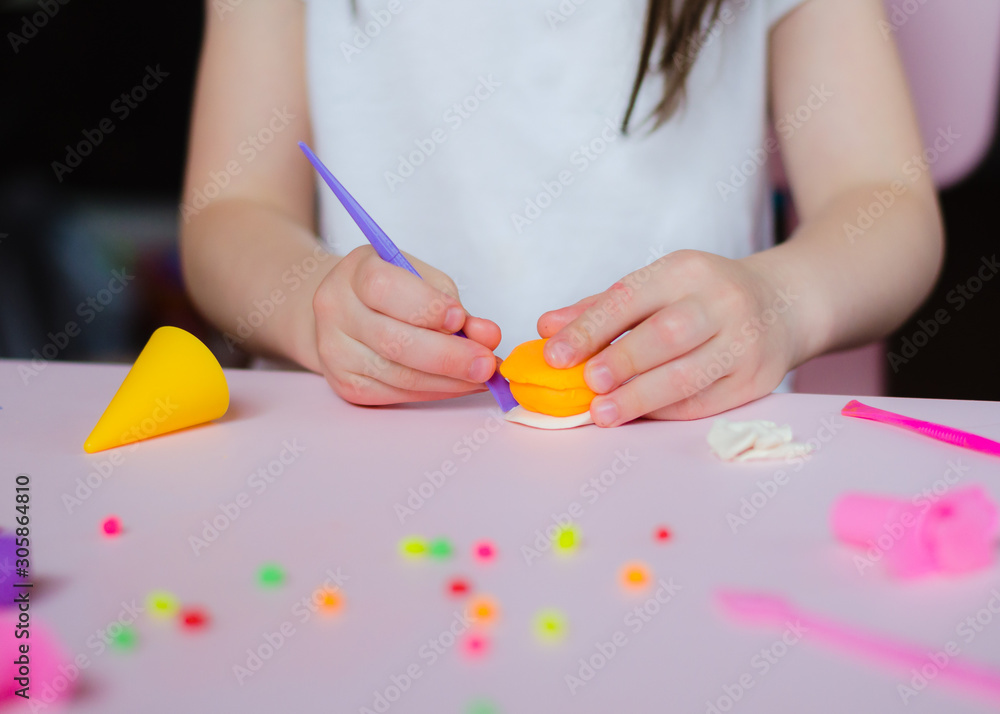 Child hands playing with colorful clay. Homemade plastiline. Girl molding modeling clay. Homemade clay. Child playing and creating from play dough.