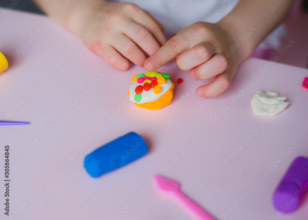 Child hands playing with colorful clay. Homemade plastiline