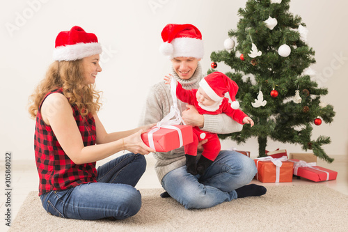 Happy couple with baby celebrating Christmas together at home.