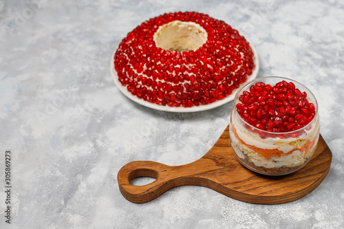 Salad Garnet bracelet. Vegetable salad with pomegranate seeds with pomegranate on concrete background