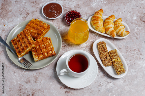 Delicious breakfast with coffee, orange juice, waffles,croissants,jam,nut paste on light background,top view