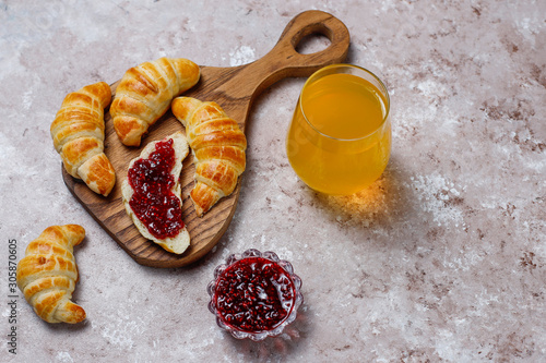 Fresh tasty homemade croissants with raspberry jam on grey-white background. French pastry