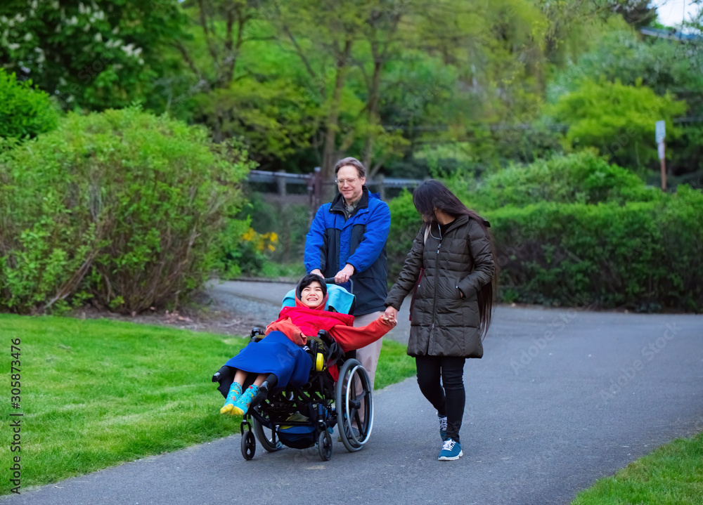 Disabled child in wheelchair at park with father and sister Disabled child in wheelchair at park with father and sister