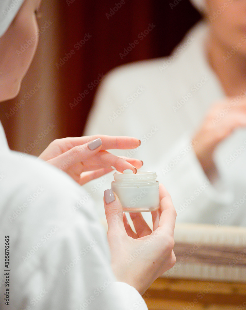 woman taking face-cream with her finger in the bathroom woman taking face-cream with her finger in the bathroom