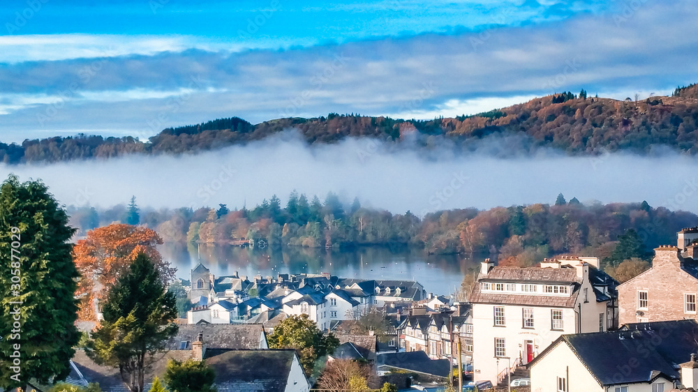 Aerial top view over Bowness On Windermere on an early morning with fog and mist rising on lake Windermere. Autumn in the Lake District, Cumbria, UK. 