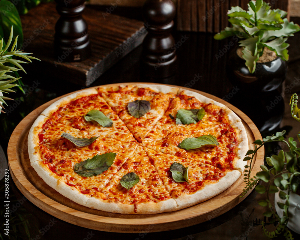 margarita pizza topped with basil leaves served on wood pizza board