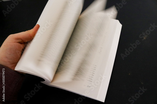 Primo piano di una mano di una donna che sfoglia le pagine di un libro, educazione e letteratura photo