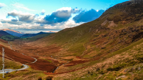 Scenic valley in autumn with snow capped mountain peaks. Touristic destination in the Lake District, Cumbria, United Kingdom. Top aerial view of peaks.