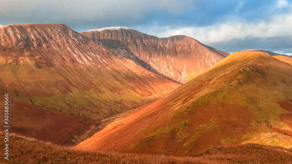 Naklejka premium Scenic valley in autumn with snow capped mountain peaks. Touristic destination in the Lake District, Cumbria, United Kingdom. Top aerial view of peaks.