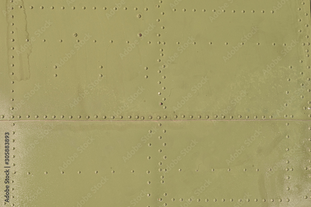 Old green metal surface of the aircraft fuselage with rivets