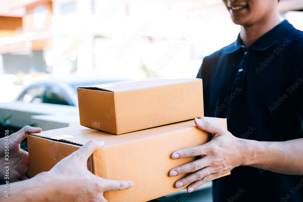 Asian cargo carrier holds a cardboard box with the package inside and the recipient is signing the package. Asian cargo carrier holds a cardboard box with the package inside and the recipient is signing the package.