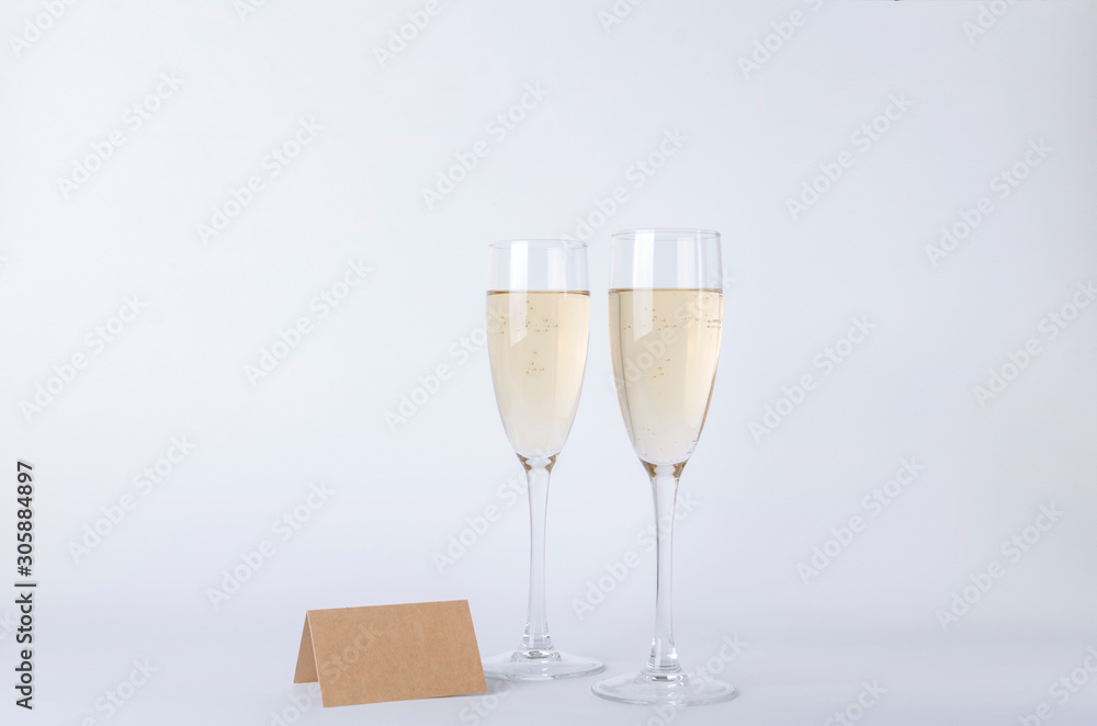 Pair of glasses full of champagne and blank place card on the gray background Pair of glasses full of champagne and blank place card on the gray background