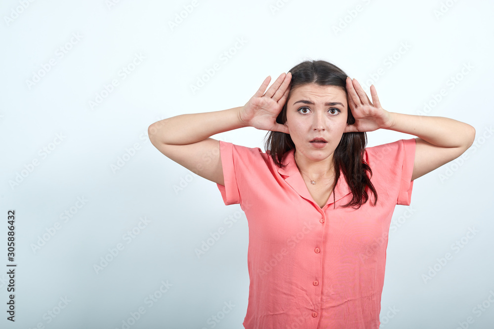 Attractive young woman in pink shirt isolated on white background in studio, holding hand on head, looking scared. People sincere emotions, lifestyle concept. Attractive young woman in pink shirt isolated on white background in studio, holding hand on head, looking scared. People sincere emotions, lifestyle concept.