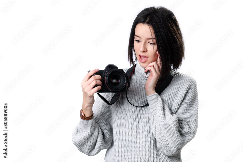teenage girl in looking at the photo camera in her hands with curious and surprised expression on her face