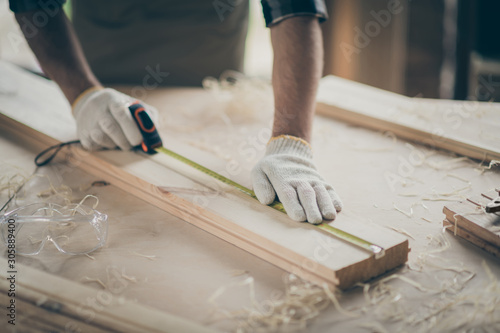 Cropped close-up view of his he nice hands swearing gloves skilled experienced guy expert measuring plank board building new house project start-up at modern industrial loft style interior indoors