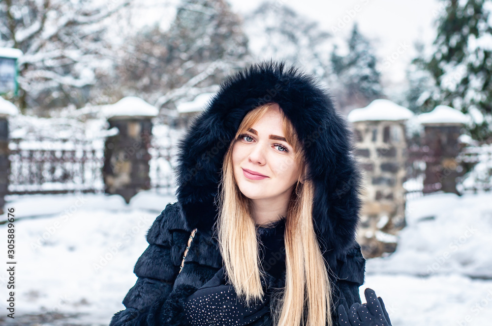 Young pretty girl of model appearance in a natural black fur coat basks in the snowy winter against the backdrop of a city park. Fashion. Style. Winter clothes made of natural fur. Fur coats. Young pretty girl of model appearance in a natural black fur coat basks in the snowy winter against the backdrop of a city park. Fashion. Style. Winter clothes made of natural fur. Fur coats.