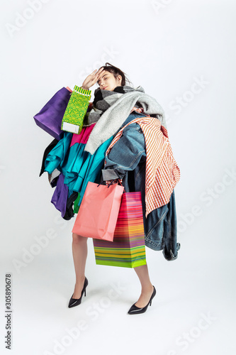 Shopping like an issue. Woman addicted of sales. Overproduction and crazy demand. Female model wearing too much colorful clothes, need more. Fashion, style, black friday, sale, abusing purchases.