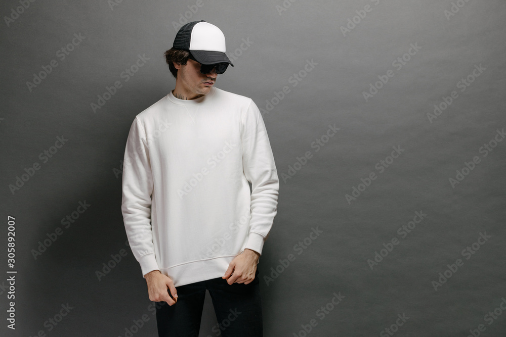 Man wearing blank white sweatshirt and empty baseball cap standing over  gray background. Sweatshirt or hoodie for mock up, logo designs or design  print with free space. Photos | Adobe Stock