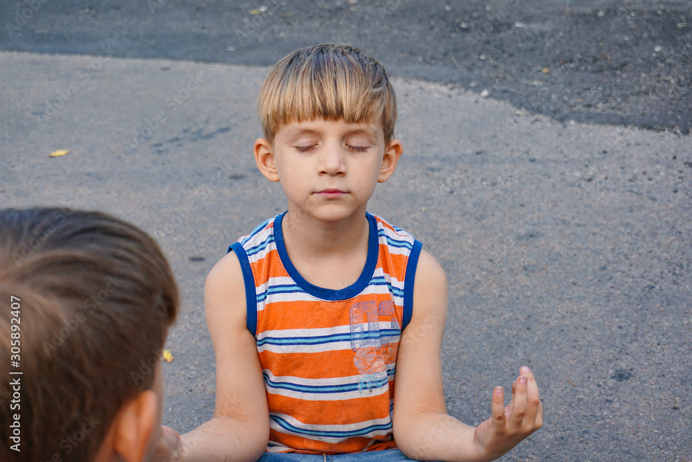 Two boys are meditating sitting on the pavement in the middle of the road. Two boys are meditating sitting on the pavement in the middle of the road.
