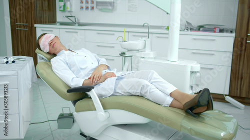 Tired doctor sleeps on a dental chair