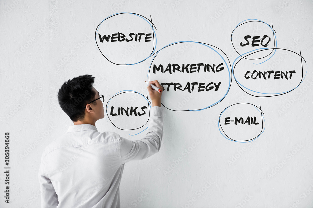 back view of seo manager writing on wall with illustration of concept words of marketing strategy back view of seo manager writing on wall with illustration of concept words of marketing strategy