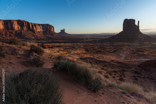 Sunset light over the desert in Monument Valley, AZ. A landscape view of the western mitten and the mesas and the mountains at the back. © Xavi