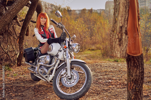 red-haired female biker sitting on a white motorcycle photo