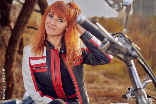 Close-up of a red-haired female biker sitting on a motorcycle. photo