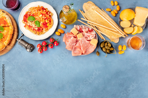 Italian food. Pizza, pasta, cheese, hams, wine and olive oil, shot from the top with copy space, a flat lay composition
