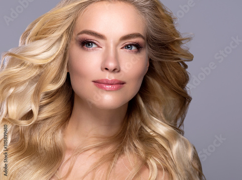 Blonde woman long curly hair face close up beautiful female natural makeup