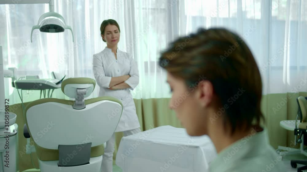Girl drinks soda, dentist looks at her disapprovingly Girl drinks soda, dentist looks at her disapprovingly