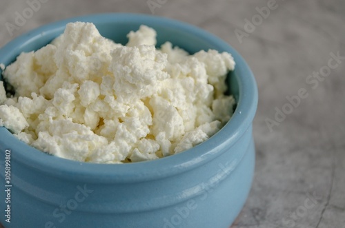 Cottage cheese in blue glass stands on a wooden table. Healthy breakfast. Close-up
